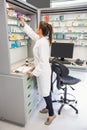 Junior pharmacist taking medicine from shelf Royalty Free Stock Photo