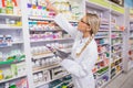 Junior pharmacist taking medicine from shelf