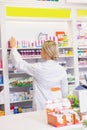 Junior pharmacist taking medicine from shelf Royalty Free Stock Photo