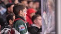 Junior schoolboy fan of hockey team cheering at glass sidebar