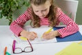 A junior schoolgirl with glasses writes something with her left Royalty Free Stock Photo