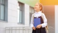 Junior schoolgirl holding book walks home with good mood