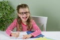 A junior schoolgirll in glasses writing something in copybook a Royalty Free Stock Photo