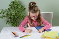 A junior schoolgirll in glasses writing something in copybook a Royalty Free Stock Photo