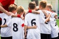 Junior soccer football team stacking hands with coach before a match