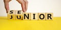 From junior to senior symbol. Businessman turns cubes and changes the word `junior` to `senior`. Beautiful yellow table, white Royalty Free Stock Photo