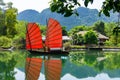 Junk. Beautiful traditional vietnamese boat with red sails on a picturesque lake in the jungle. Red sails reflected in the water