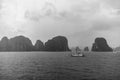 A junk boat sails across Ha Long Bay, Vietnam, with rain in the foreground and mist in the distance