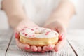 Junk-food and eating concept - close up of female hand holding glazed donut