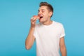 Junk food. Happy delighted man in casual white t-shirt eating donut with expression of big pleasure