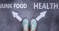 Junk food and health as different choices in life - pictured as words Junk food, health on a road to symbolize making decision and