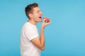 Junk food. Side view of delighted man in white t-shirt eating donut with expression of big pleasure