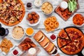 Junk food table scene. Pizza, hamburgers, chicken wings and salty snacks. Top down view over a white wood background. Royalty Free Stock Photo