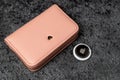 Jurmala, Latvia - 21 09 2023: On table silver AirTag Apple and pink wallet. Air Tag gadget to track of your stuff and