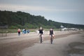 JURMALA, RIGA - AUGUST 25, 2023: Selective blur on two men, friends, biking and riding together bicycles on a beach in Jurmala