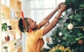 Just adding my own touch of magic to the decorations. an attractive young businesswoman decorating a Christmas tree in
