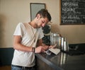 Just another day in the life of a barkeep. a focussed young bartender making notes on receipts behind the bar. Royalty Free Stock Photo