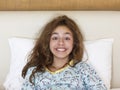 Just awake pretty teenager girl with funny emotion face and wild hair on the bed