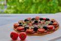 Just backed veggie pizza with mushrooms, black olives and herbs on the gray kitchen table decorated with fresh cherry tomatoes Royalty Free Stock Photo