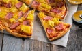 Just baked hawaiian pizza with freshly chopped pineapple and ham on the rustic wooden background. Selective focus