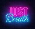 Just Breath neon lettering on brick wall background.