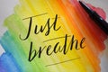 JUST BREATHE hand-lettered on rainbow watercolor background