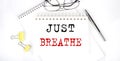 Just Breathe text on the notebook with pen,clips and glasses Royalty Free Stock Photo