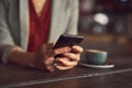 Just at the cafe around the corner. an unidentifiable woman texting on a cellphone in a cafe. Royalty Free Stock Photo