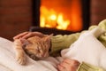 Just chilling by the fireplace - woman hands petting a small tabby cat Royalty Free Stock Photo