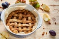 Just cooked homemade american apple pie in baked form on brown wooden table with raisins and fresh fruits - apples, grapes, plums Royalty Free Stock Photo