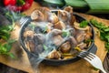 Just cooked steaming porcini mushrooms in the frying pan on the wooden table. Top view