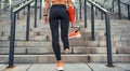 Just do it. Back view of disabled women in sports clothing holding her leg prosthesis while standing on stairs outdoors