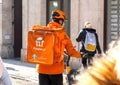 Just Eat Takeaway Pyszne.pl driver, fast food delivery bike rider with a Pyszne pl orange backpack with the brand logo, rear view Royalty Free Stock Photo