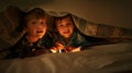 Just five more minutes. Two young brothers coloring in pictures while underneath their blanket after their bedtime. Royalty Free Stock Photo