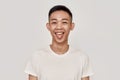 Just Fun. Portrait of cheerful young asian man with clean shaven face sticking his tongue out and looking at camera