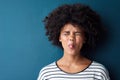 Just goofing around. Studio portrait of an attractive young woman sticking her tongue out against a blue background. Royalty Free Stock Photo