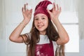 just having fun. happy child wear cook uniform. chef girl in hat and apron. kid cooking food in kitchen. choosing a Royalty Free Stock Photo