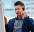 Just having satisfied customers isnt good enough anymore. a young man using a headset and computer.at work in a modern Royalty Free Stock Photo