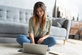 Just inspired. Confident young beautiful smiling woman working on laptop while sitting on the floor at home. Royalty Free Stock Photo