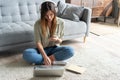 Just inspired. Confident young beautiful smiling woman working on laptop while sitting on the floor at home. Royalty Free Stock Photo