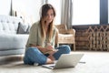 Just inspired. Confident young beautiful smiling woman working on laptop while sitting on the floor at home. Royalty Free Stock Photo