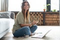 Just inspired. Confident young beautiful smiling woman working on laptop while sitting on the floor at home. Royalty Free Stock Photo