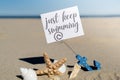 JUST KEEP SWIMMING text on paper greeting card in anchor paper holder and starfish seashell summer vacation decor. Sandy