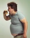 Just a little bit wider. Studio shot of an overweight man biting into a burger.