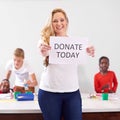 Just a little goes a long way. Portrait of a volunteer holding up a donate today sign while working with little children