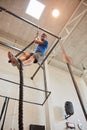 Just a little longer. Low angle shot of a handsome young man rope climbing while working out in the gym. Royalty Free Stock Photo