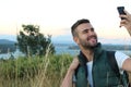 Just look! I am here! Handsome young man carrying backpack and taking a picture of himself and pointing to the gorgeous view Royalty Free Stock Photo