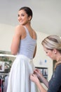 Just making a few small adjustments. A dressmaker making some adjustments to a young womans skirt inside a fabric shop.