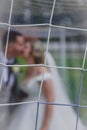 Just married couple behind the net kissing on the football soccer pitch. Royalty Free Stock Photo