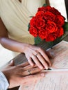 Just married couple hands with white gold rings, marriage certificate and red roses bouquet close up, Royalty Free Stock Photo